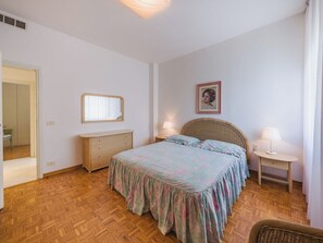 Ein Schlafzimmer mit Bett, Kommode, Nachttischlampen und einem Spiegel.