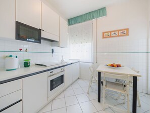 A kitchen with white cabinets, a microwave, a sink, and a table with a fruit bowl. - Beautiful apartment for 6 people with WIFI, A/C, TV, terrace and pets allowed (Camaiore)