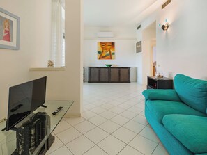 Un salon avec un téléviseur, un canapé et une cuisine en arrière-plan.