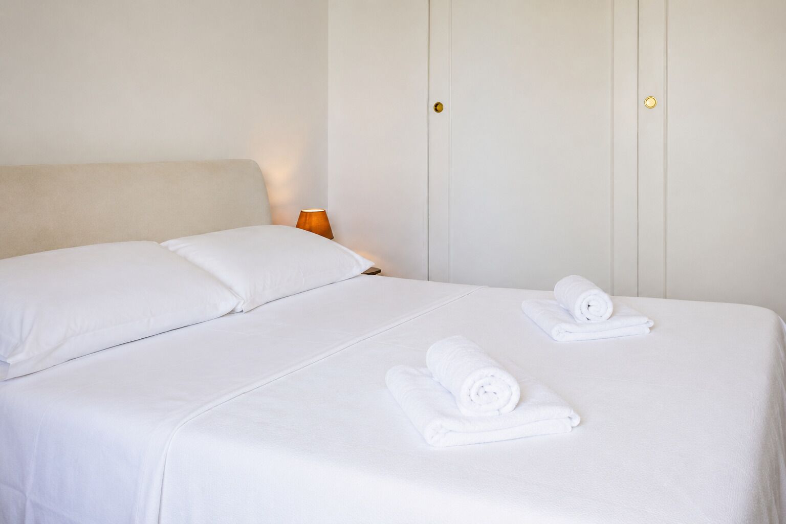 A hotel room with a bed, pillows, and neatly folded towels.