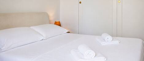 A hotel room with a bed, pillows, and neatly folded towels.