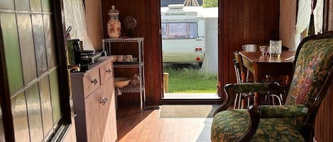 Ein gemütliches Interieur mit Holzbalkendecke, einem Essbereich mit Tisch und Stühlen sowie einer Küche mit Schränken und Herd.