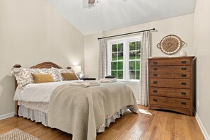 Ein Schlafzimmer mit einem Bett, einem Schminktisch, einem Fenster mit Vorhängen und einem Wanddekor.