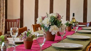 Een eettafel gedekt met borden, glazen en een bloemenstuk.