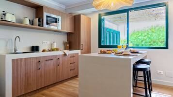 Une cuisine moderne avec des meubles en bois, un four à micro-ondes encastré et une grande fenêtre donnant sur un paysage verdoyant.