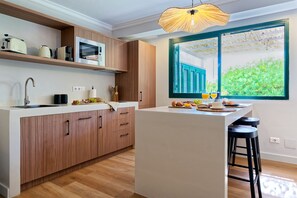 A modern kitchen with wooden cabinetry, a built-in microwave, and a large window with a view of greenery. - Villa Catalina, just a short walk from the beach in San Agustín (San Bartolomé de Tirajana)