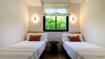 Une chambre avec deux lits, une fenêtre donnant sur un espace verdoyant et une petite table.