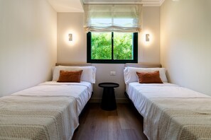 A room with two beds, a window with a view of greenery, and a small table. - Villa Catalina, just a short walk from the beach in San Agustín (San Bartolomé de Tirajana)