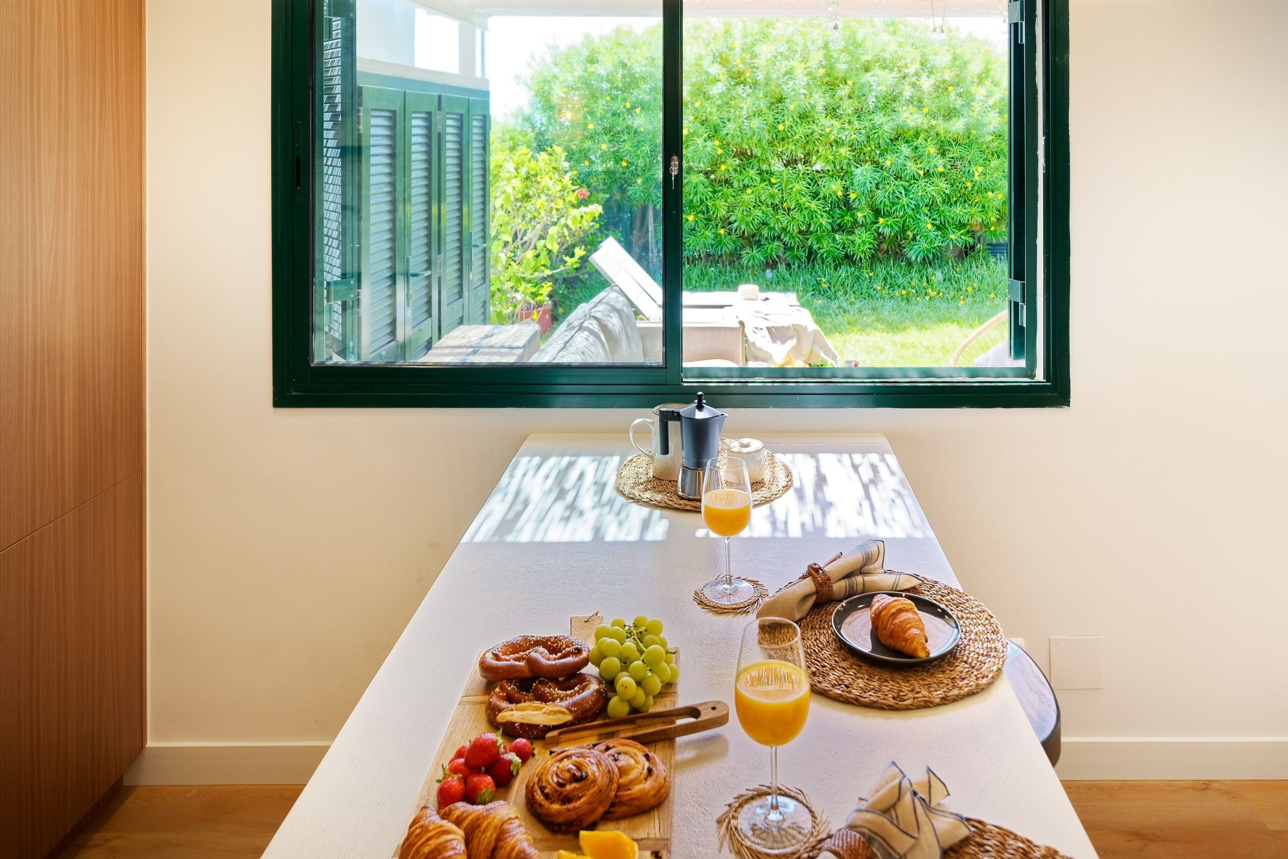 Een ontbijttafel met croissants, druiven en een glas sinaasappelsap.