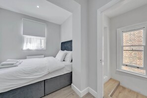 A modern bedroom with a bed, a window with a view, and a radiator. - Bright 2B Apartment by the History Museum (Greater London)