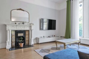 Un salon moderne avec une cheminée, un téléviseur à écran plat, un banc et une fenêtre avec des rideaux.