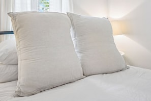 Ein Bett mit zwei großen Kissen und einer weißen Daunendecke.