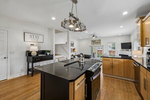 A modern kitchen with a central island, wooden cabinets, and a pendant light. - Spacious Nashville townhouse w/ exclusive backyard (Nashville)