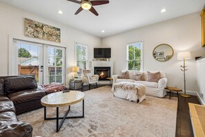 A living room with a fireplace, a ceiling fan, a television, and a large window. - Spacious Nashville townhouse w/ exclusive backyard (Nashville)