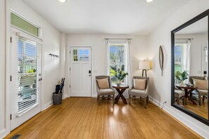 A room with wooden flooring, a door with a window, two chairs, a table, a lamp, and a large mirror. - Spacious Nashville townhouse w/ exclusive backyard (Nashville)