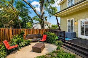 A backyard with a wooden deck, a wicker sofa, two red chairs, a small table, and a covered pool area. - Spacious Nashville townhouse w/ exclusive backyard (Nashville)