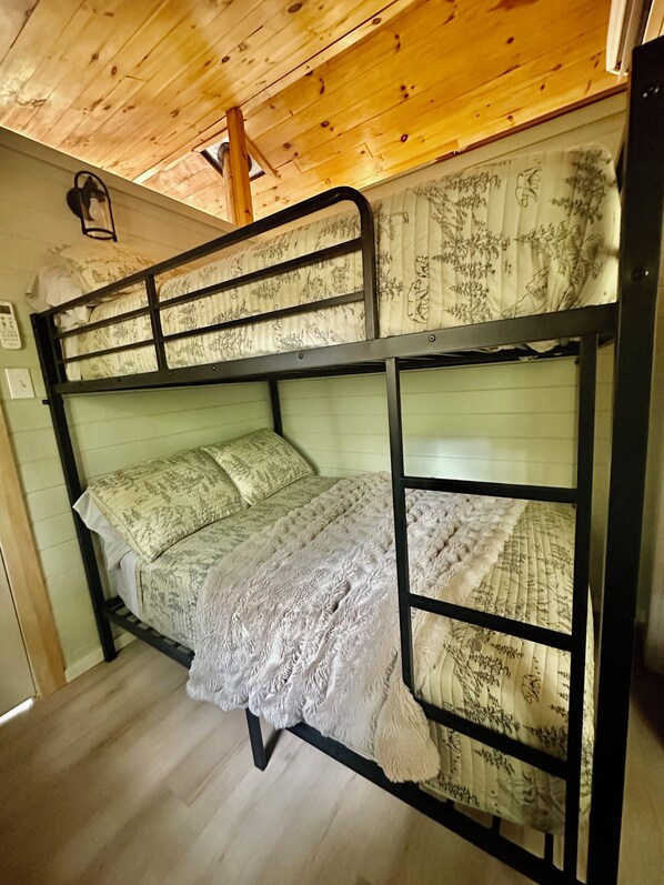 A bunk bed with a patterned bedspread and a wooden ceiling. - Private Island Cottage on Ebeemee Lake (Brownville)