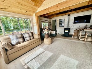Interior acogedor de una cabaña con sofá, chimenea y comedor.