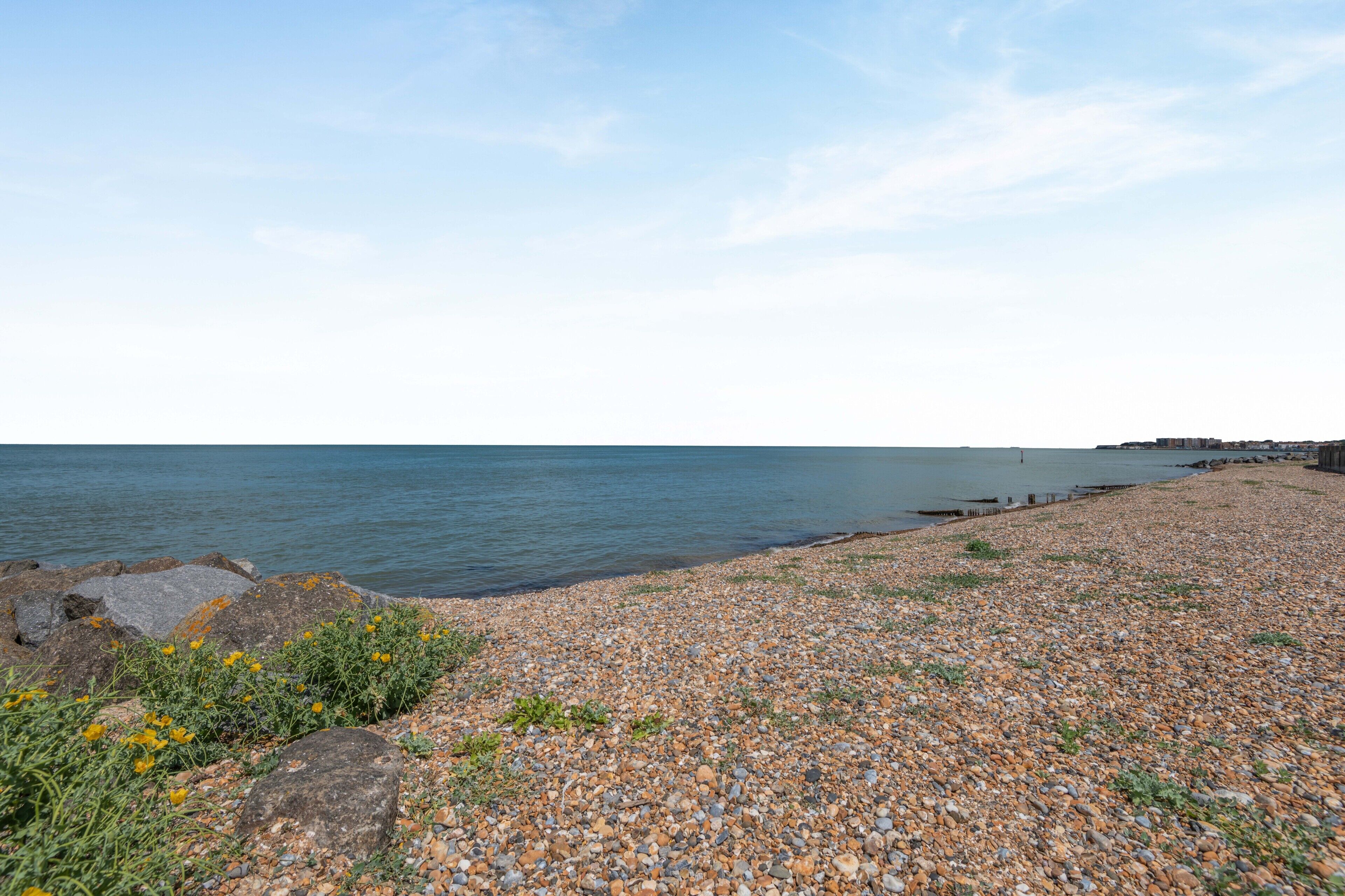 A pebble beach with a calm sea and a clear sky.