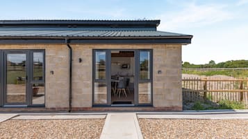 A modern building with a brick exterior, large glass doors, and a metal roof.