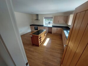 A kitchen with wooden cabinets, a black countertop, and a window. - Wold View (Market Rasen)