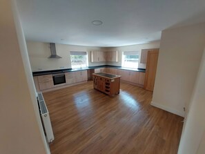 A spacious kitchen with wooden cabinets, a central island, and a built-in oven. - Wold View (Market Rasen)