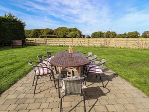 A round outdoor table with chairs, surrounded by a brick patio.