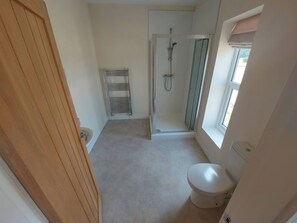 A bathroom with a shower, toilet, and a towel rack. - Wold View (Market Rasen)