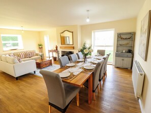 A spacious living room with a dining area, a fireplace, and a view of the outdoors.