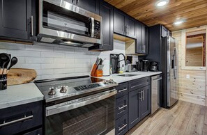 Une cuisine moderne dotée d’appareils électroménagers en acier inoxydable, d’un plafond en bois et d’un four encastré.