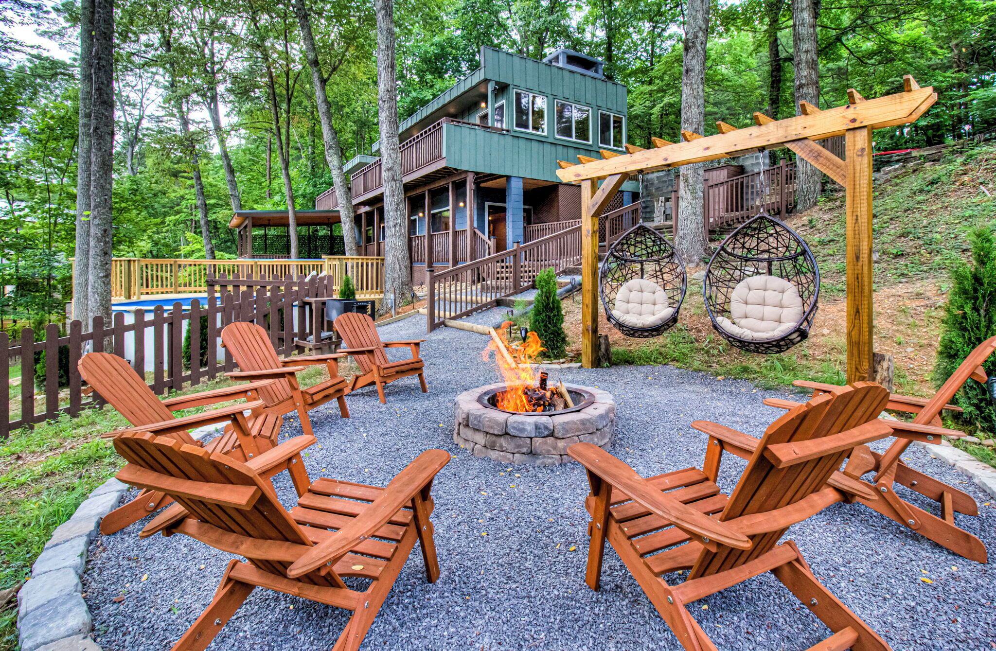 A wooden deck with Adirondack chairs, a fire pit, and a building with a balcony.