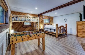 Une pièce chaleureuse avec un lit en bois, une table de baby-foot et une fenêtre.
