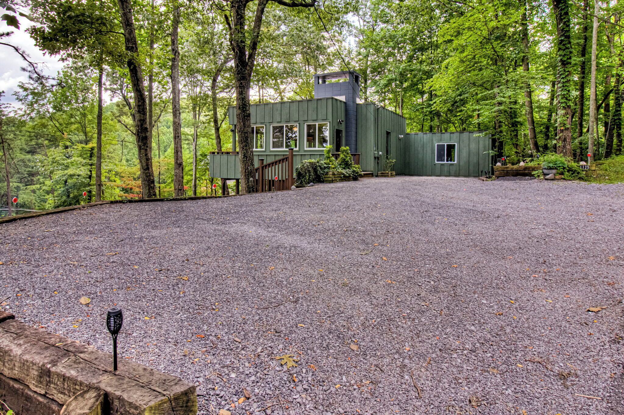 A house with a gravel driveway, surrounded by trees.