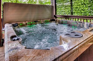 Un bain à remous doté d’une terrasse en bois et d’une rambarde en métal.