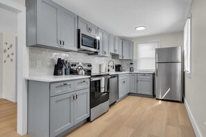 Una cocina moderna con armarios grises, electrodomésticos de acero inoxidable y un salpicadero de azulejos.
