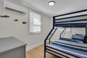 A bunk bed with a striped bedding, a desk, and an air conditioning unit on the wall. - Newly Renovated - Pet OK - 2BR Steps to Beach (Wildwood)