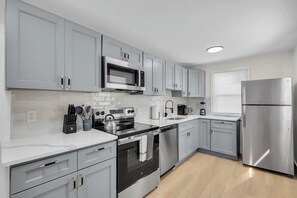 A modern kitchen with grey cabinets, stainless steel appliances, and a white countertop. - Newly Renovated - Pet OK - 2BR Steps to Beach (Wildwood)