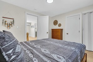 A bedroom with a bed, a dresser, and a door. - Newly Renovated - Pet OK - 2BR Steps to Beach (Wildwood)