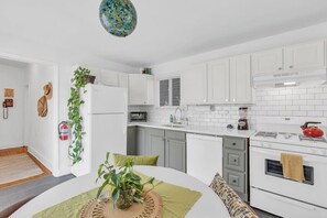A compact kitchen with white cabinets, a microwave, a stove, and a hanging plant. - Zen Retreat in Asbury Park with Patio & Parking (Asbury Park)