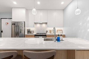 A modern kitchen with a large island, stainless steel appliances, and pendant lighting. - Revelhaus | Boutique Mountain Retreat (Revelstoke)
