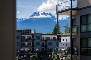 En modern byggnad med balkonger som vetter ut mot ett bergigt landskap.