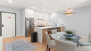 Una cocina moderna con una isla central, electrodomésticos de acero inoxidable e iluminación colgante.