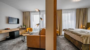 Ein Hotelzimmer mit Bett, Schreibtisch, Stuhl, Fernseher und einem Fenster mit Vorhängen.