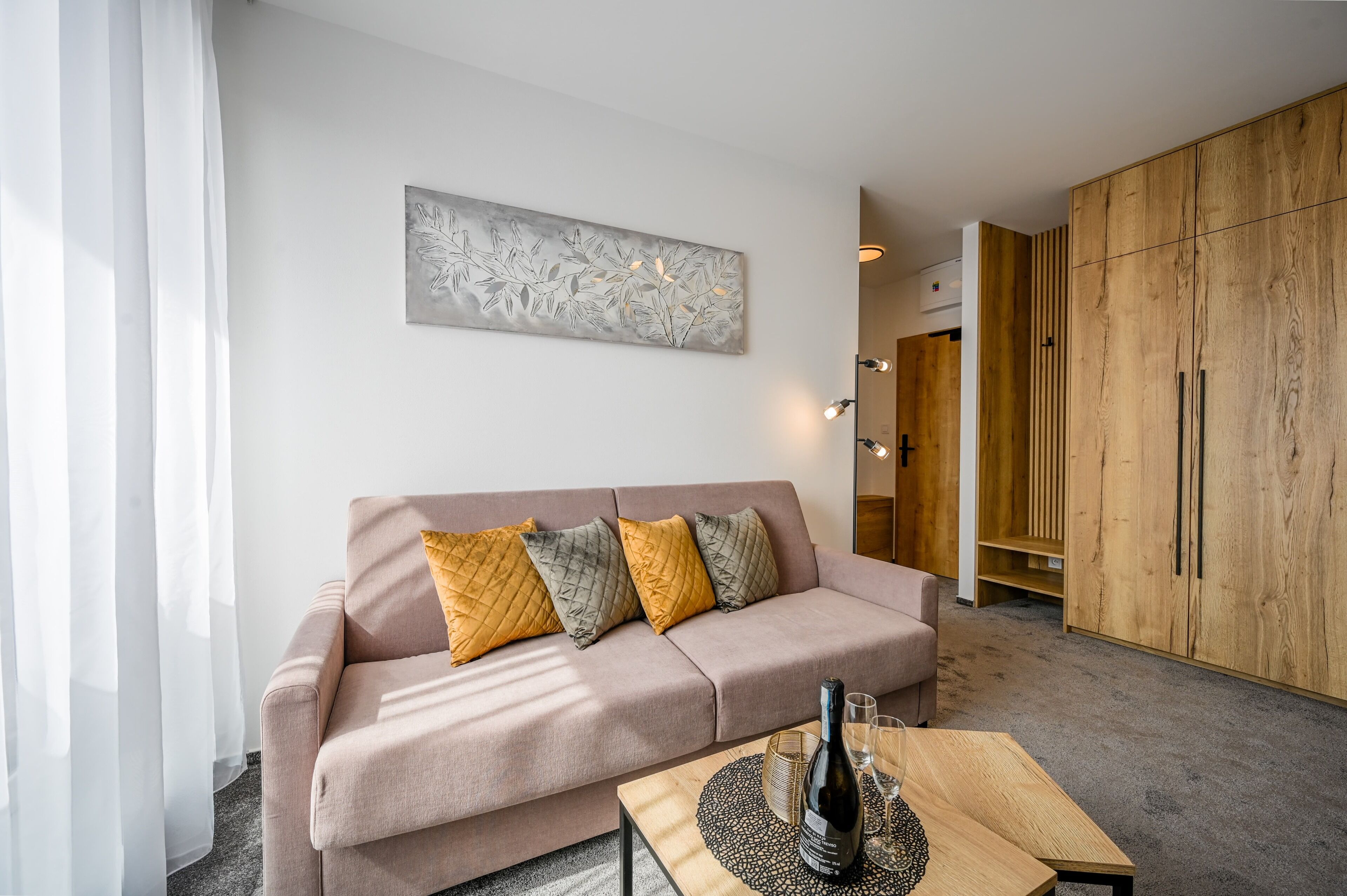 Ein modernes Wohnzimmer mit einer Couch, dekorativen Kissen, einem Wandbild und einem Holzkabinett.