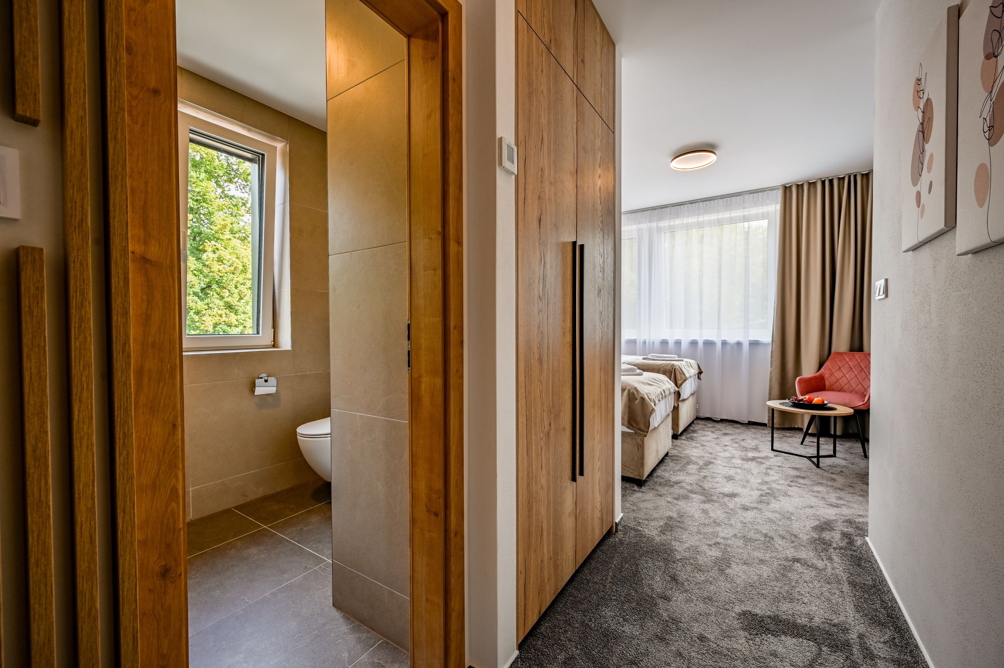 Una habitación de hotel con baño, cama, una mesita y una silla.