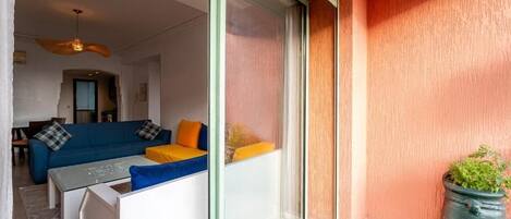 Una sala de estar moderna con un conjunto de sofá, una mesa de centro y un ventanal corredizo que da a un espacio exterior.
