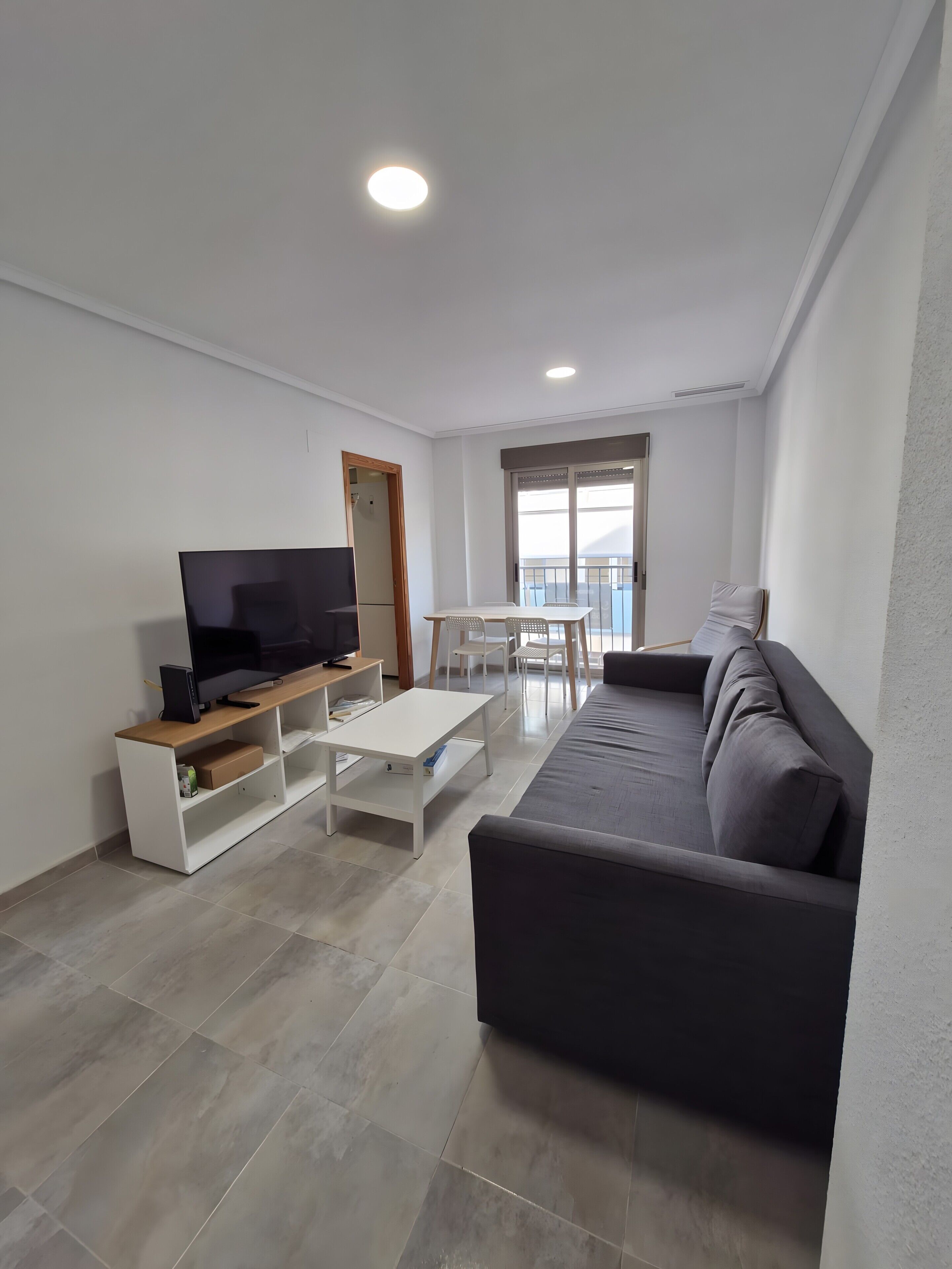 Un salon moderne doté d’un téléviseur à écran plat, d’un canapé, d’une table basse et d’un coin repas avec des chaises.