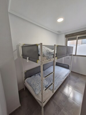 A bunk bed with a window above it, a white wall, and a tiled floor. - Holiday Home 'Santa Pola Centro Con Parking' with Balcony, Wi-Fi and Air Conditioning (Santa Pola)