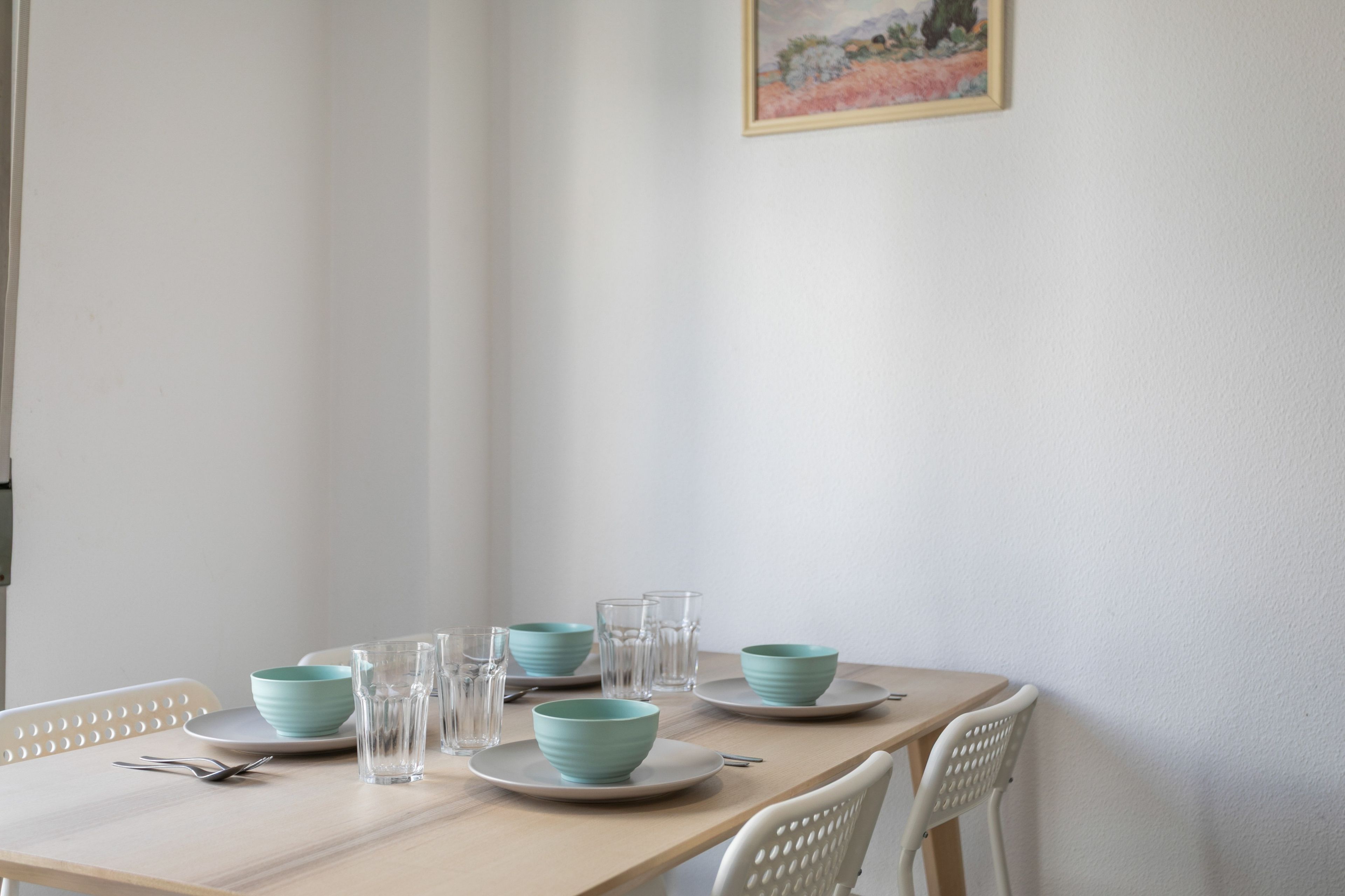 A dining table with plates, bowls, and glasses set for four.