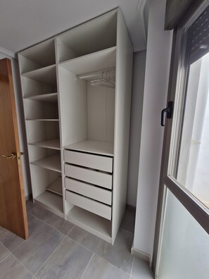 A walk-in closet with open shelves, a hanging rod, and a sliding door. - Holiday Home 'Santa Pola Centro Con Parking' with Balcony, Wi-Fi and Air Conditioning (Santa Pola)